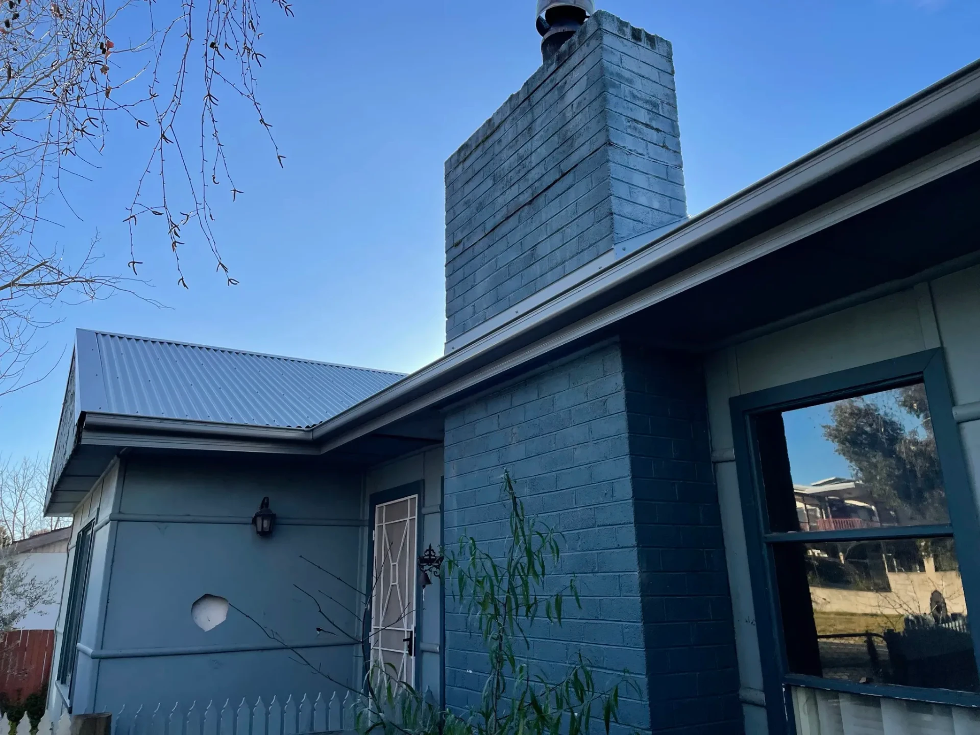 House corner showing new metal roofing, brick chimney and neat flashing details