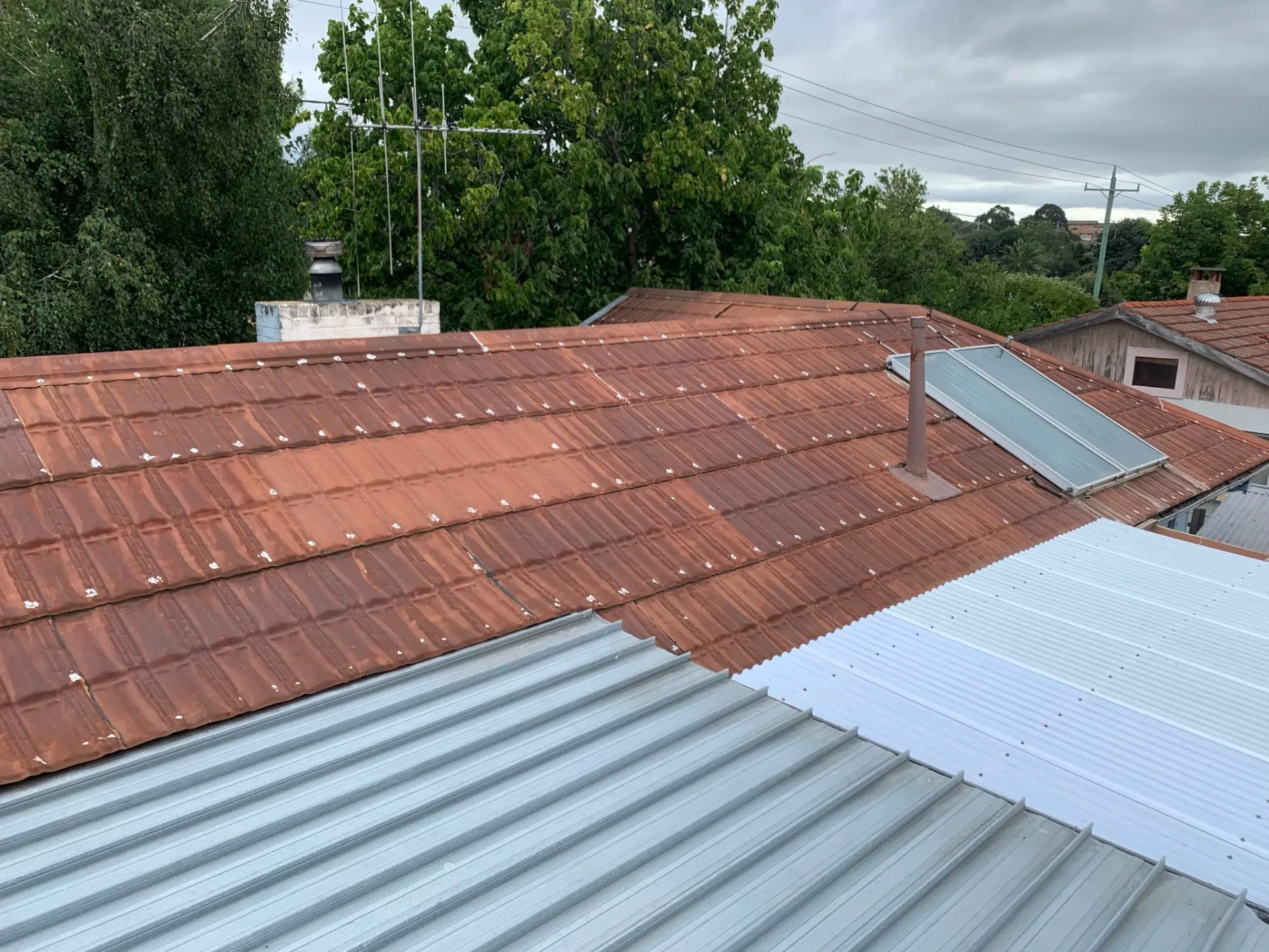 Roof transition showing old terracotta tiles alongside new COLORBOND metal sheeting