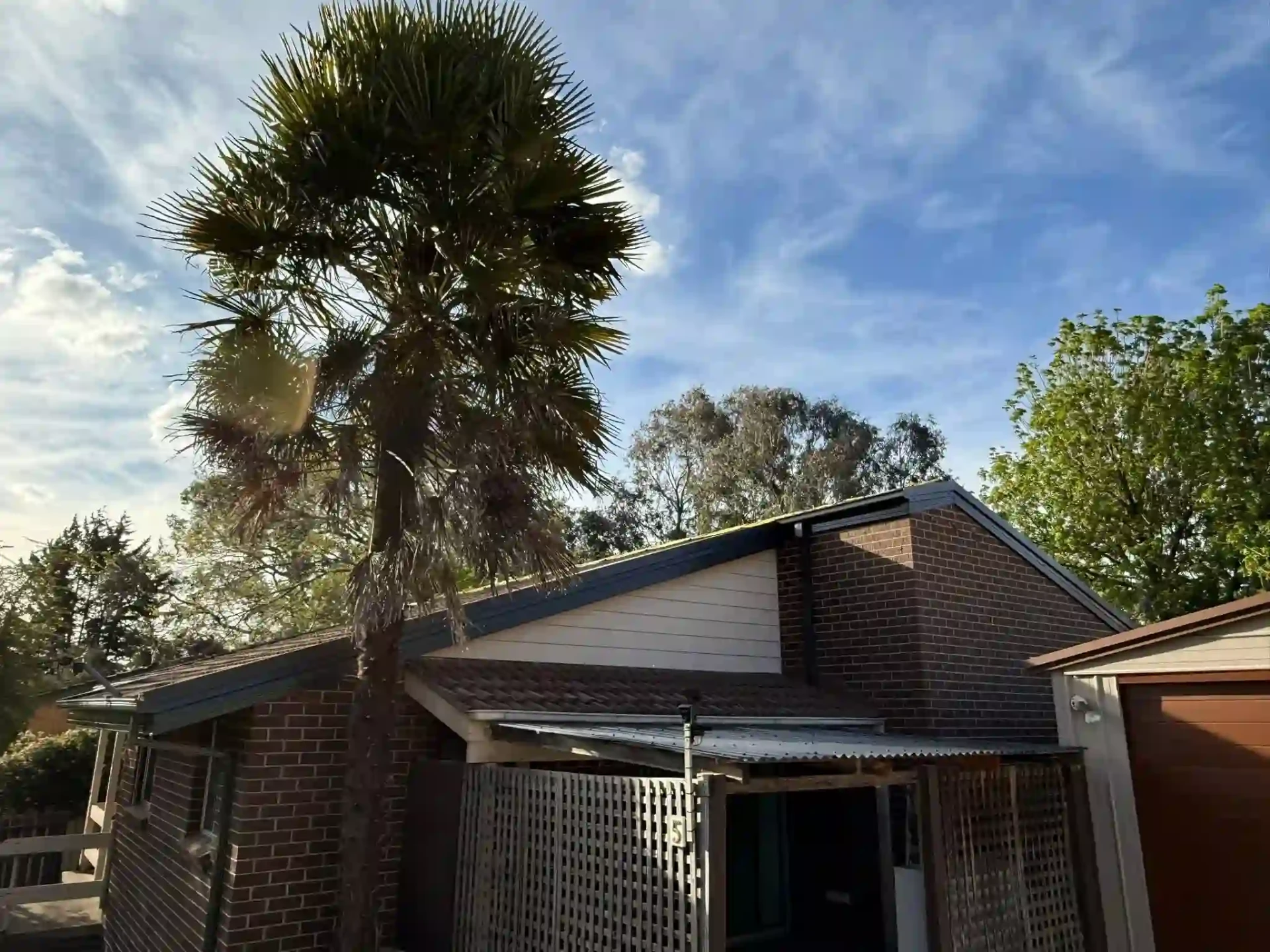 Queanbeyan brick home with new dark roof, fascia and guttering under a blue sky